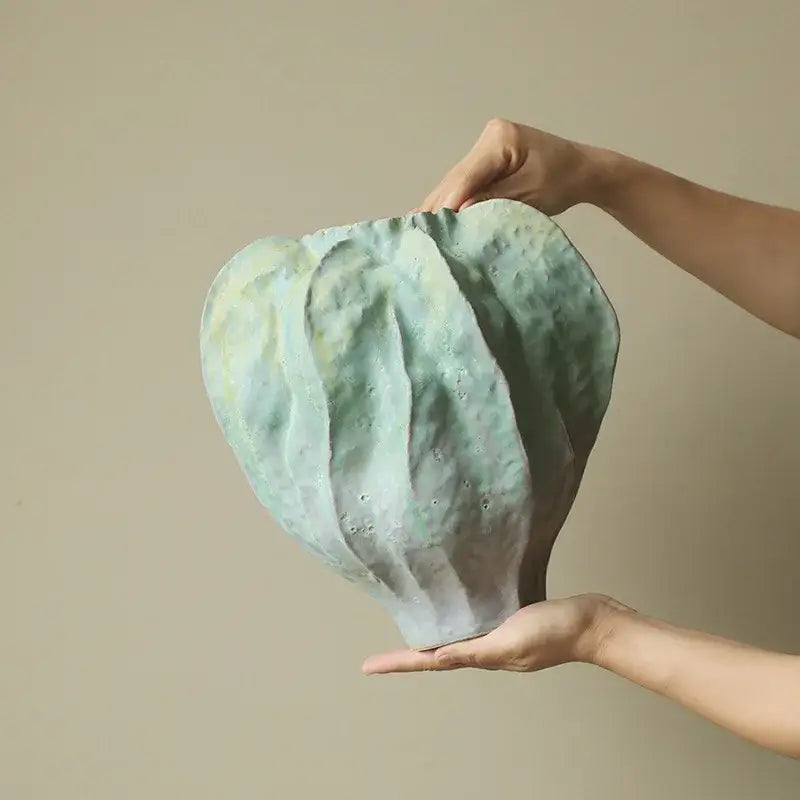 Abstract mint and olive ceramic vase with textured light green surface and irregular folds for living room decor