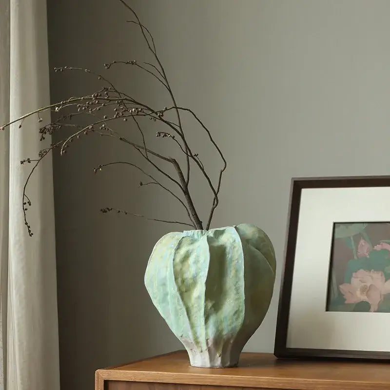 Light green abstract ceramic vase with irregular folds and textured ribbed design for living room decor
