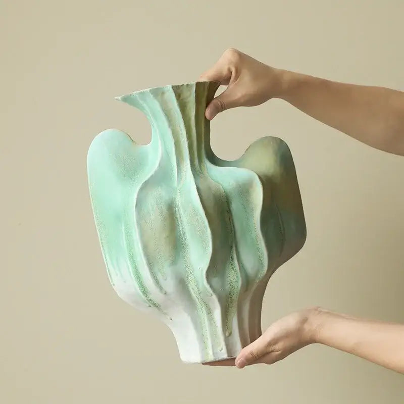 Abstract mint and olive ceramic vase with irregular folds and flowing organic curves for living room decor