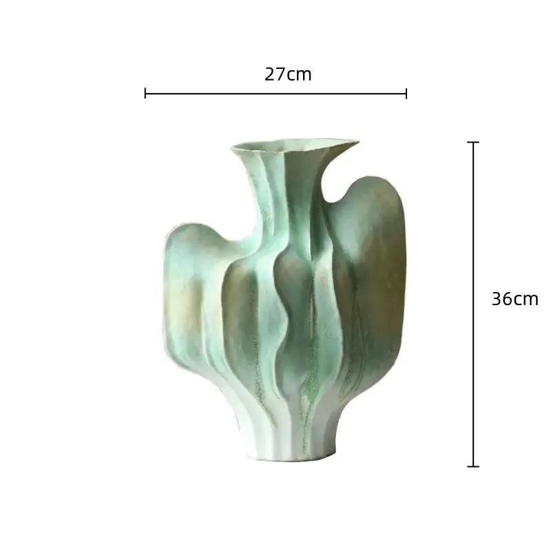 A sculptural ceramic vase with abstract irregular folds in muted mint and olive glaze for living room decor