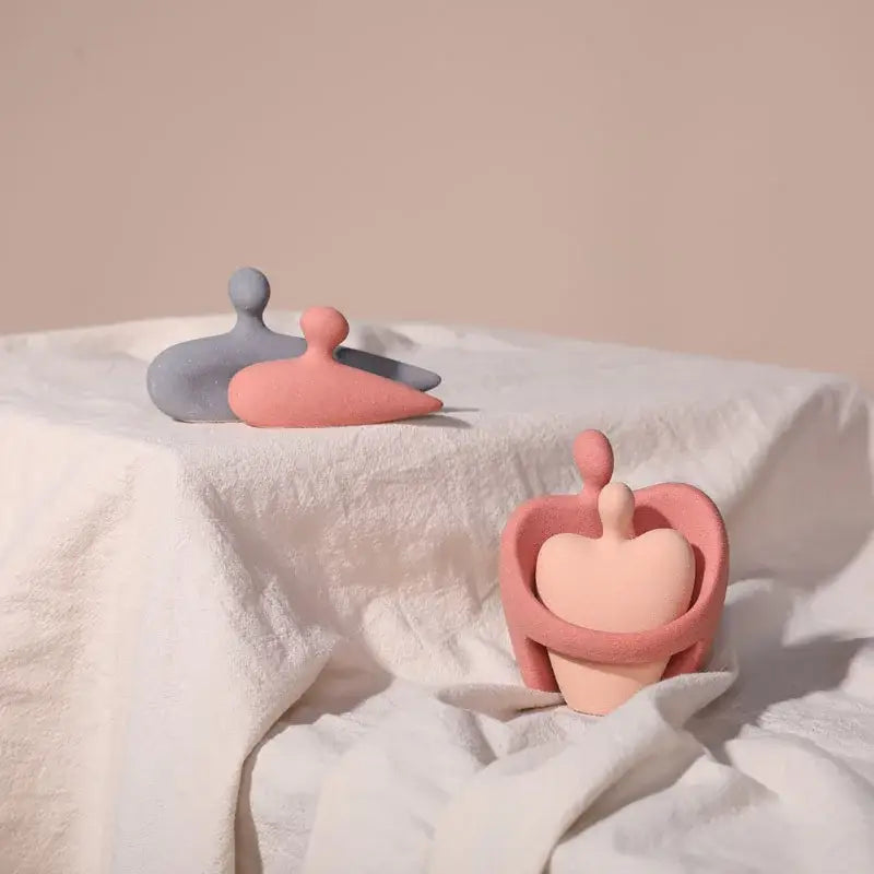 Abstract pink and beige ceramic art couple statue featuring a pastel pink figurine with a heart-shaped cradle