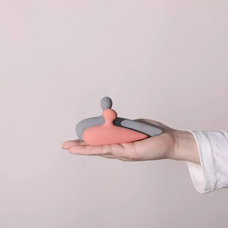 A soft pink and gray ceramic art couple statue with minimalist rounded design for living room decor