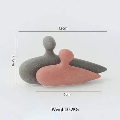 Two minimalist ceramic art couple statue figurines in matte gray and soft pink with speckled texture for living room decor