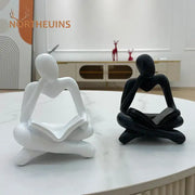 White and black abstract resin book figurines depicting seated human figures in meditative pose for office decorbites decor