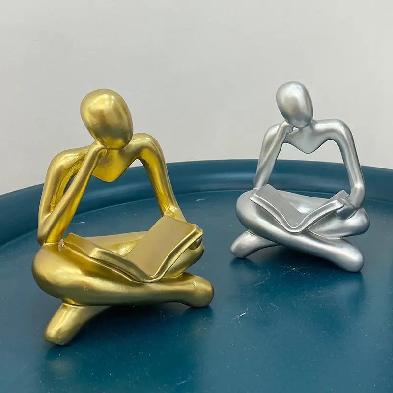 Golden and silver abstract resin book figurines depicting seated thinkers for black and white office decorbites abstract resin