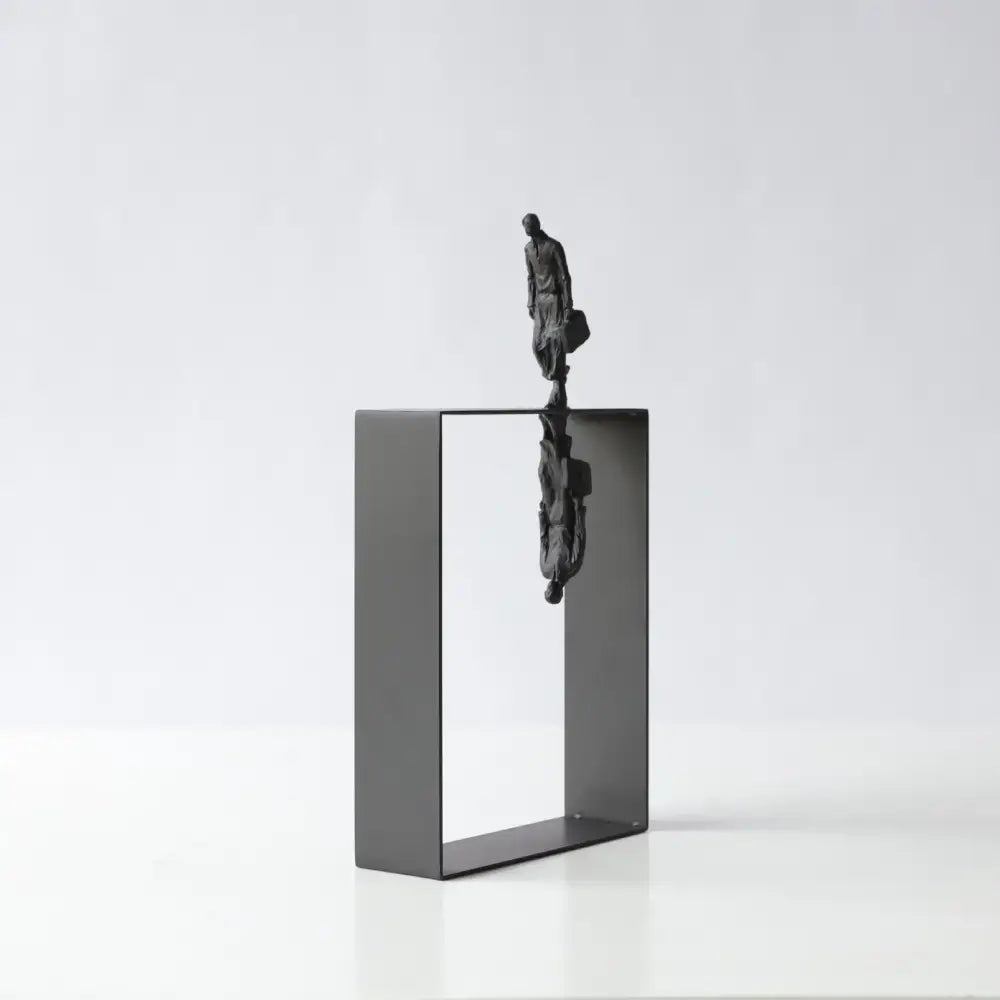 Black metallic abstract resin sculpture of a man carrying a briefcase standing on an open frame with reflection decorbites decor
