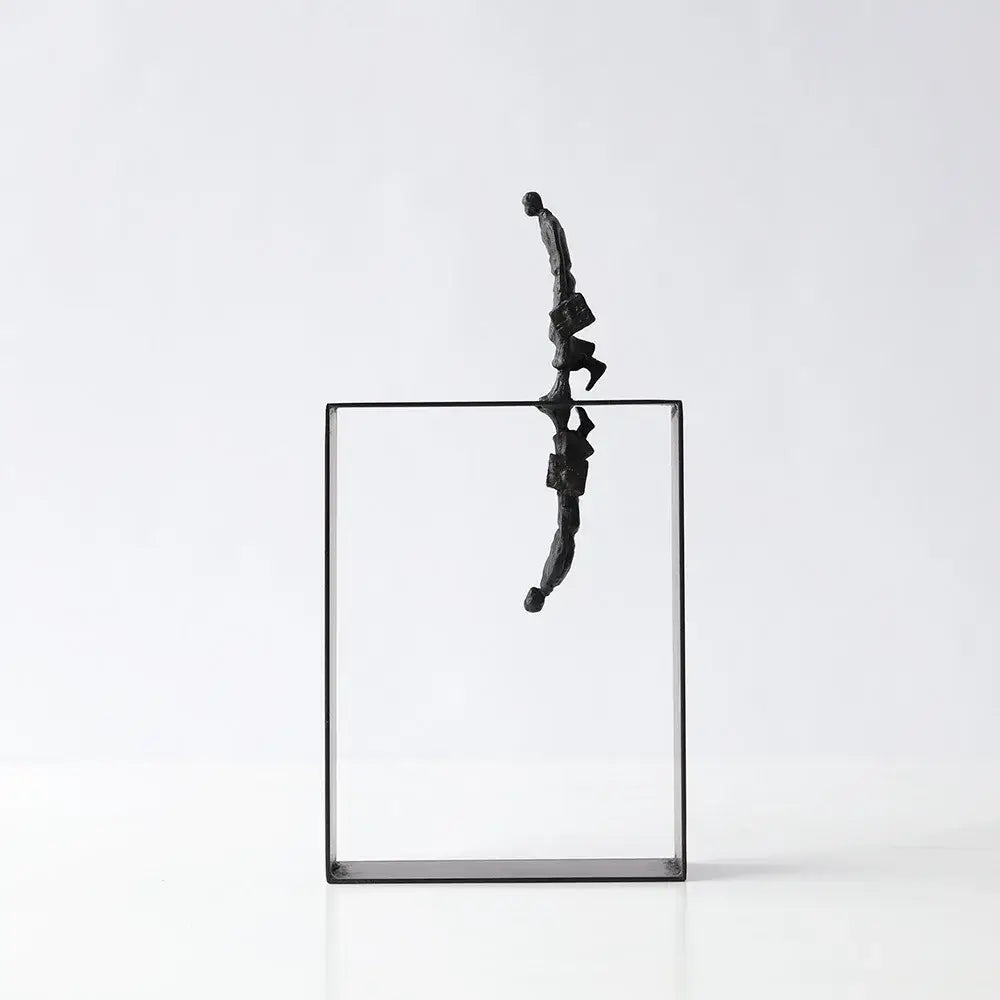 Black metallic resin sculpture of a man carrying a briefcase balanced on a glass frame for living room decorbites abstract resin decor