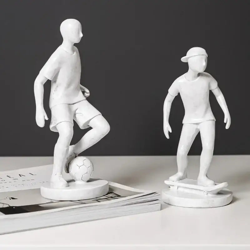 White resin abstract sports player sculpture set featuring two stylized boys with soccer ball and skateboard decorbites abstract sports