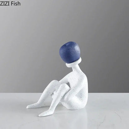 Abstract thinker resin figurine in white speckled with blue spherical head in an abstract seated pose for living room decor