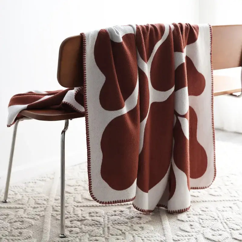 A cozy cream and rust-colored decorbites jacquard imitation cashmere throw blanket with soft fleece and modern leaf pattern
