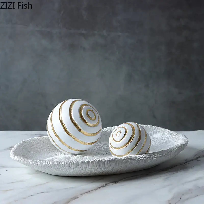 Abstract white and gold ceramic golden texture balls with spiral stripes on a textured tray for living room decor