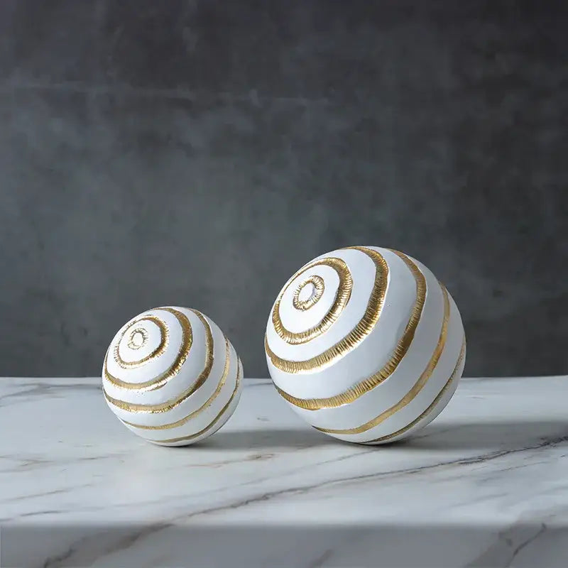 Two white ceramic spheres with golden texture spiral stripes in abstract golden texture ball living room decor
