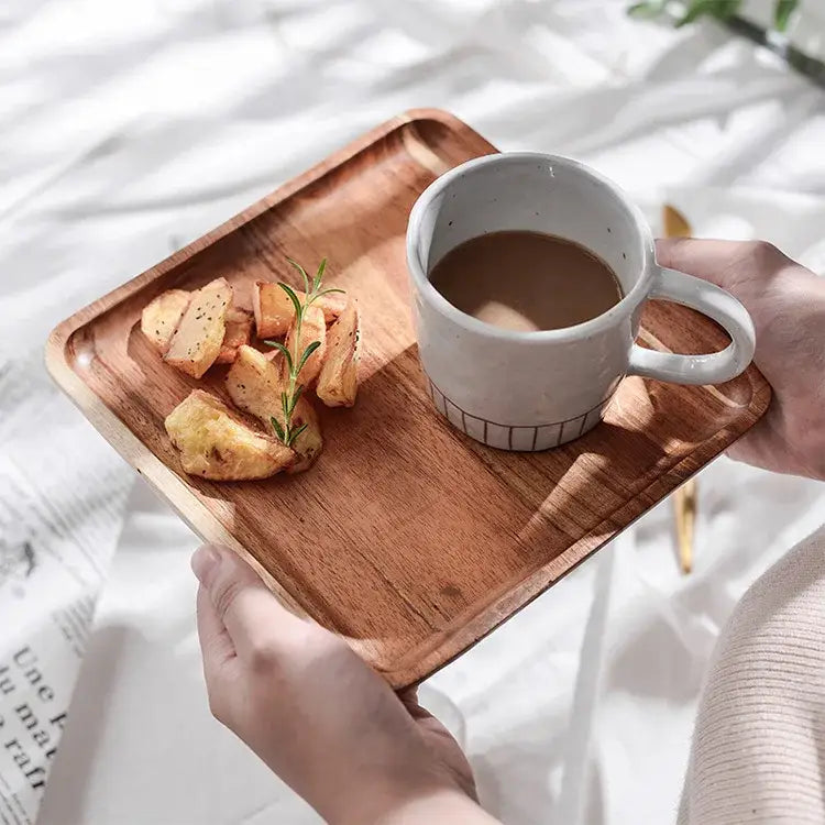 Acacia wood breakfast tray with natural wood grain finish holding white ceramic mug and roasted potatoes with rosemary