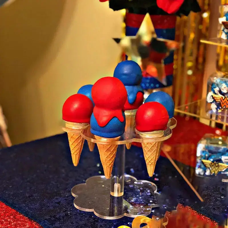 Red and blue ice cream cone cake pops displayed on a clear acrylic ice cream cone holder for kitchen baking use