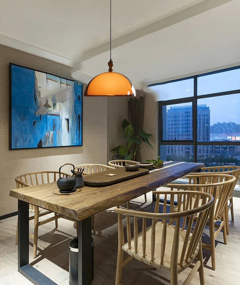 Acrylic pendant light with dark wood lampshade hanging above a rustic wooden dining table with metal legs