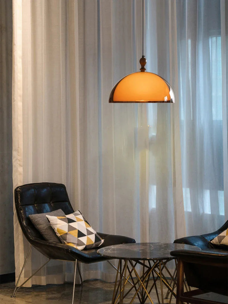 A warm amber acrylic pendant light with a polished brass finish and dark wood lampshade hanging from ceiling