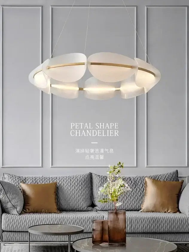 Modern white acrylic ring chandelier with gold accents hanging above a gray sofa in a dining room setting