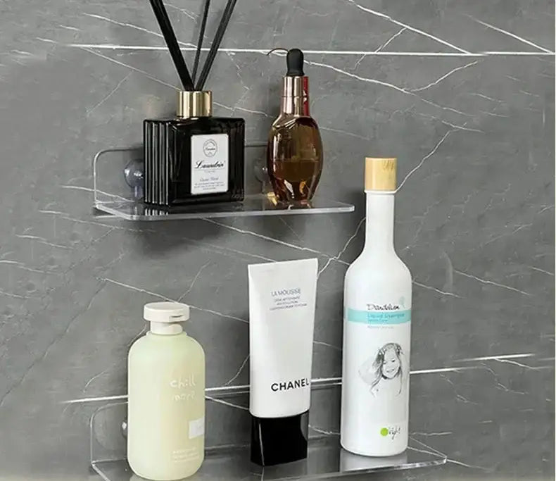 Clear acrylic DecorBites™ wall shelf organizer holding a black diffuser amber bottle and white Chanel tube for home decor