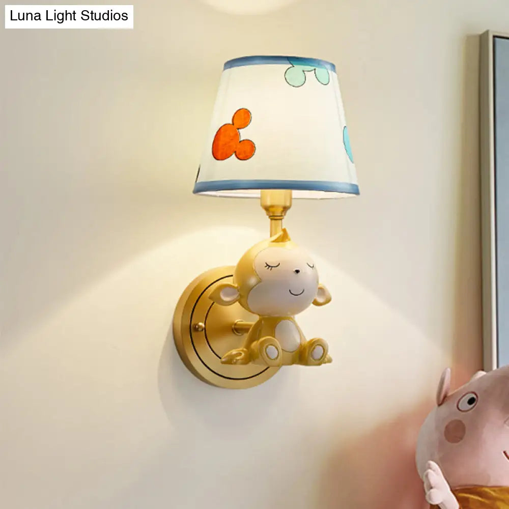 Adorable lámpara de pared con forma de mono de dibujos animados, con estructura de latón y pantalla de tela.