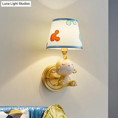 Adorable lámpara de pared con forma de mono de dibujos animados, con estructura de latón y pantalla de tela.