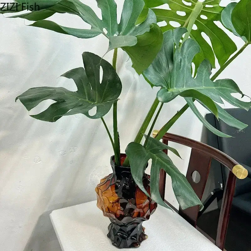 A vibrant green monstera plant displayed in a decorbites irregular amber and black glass vase for bedroom decorbites irregular glass