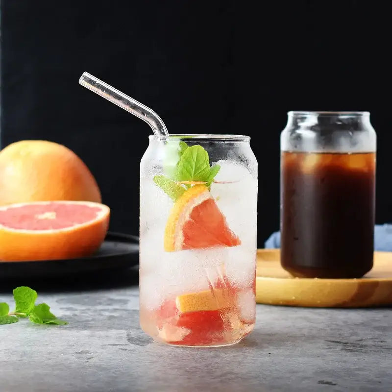 Aesthetic drinking glasses set with clear glass, lids, and straws filled with ice, grapefruit slices, and mint leaves