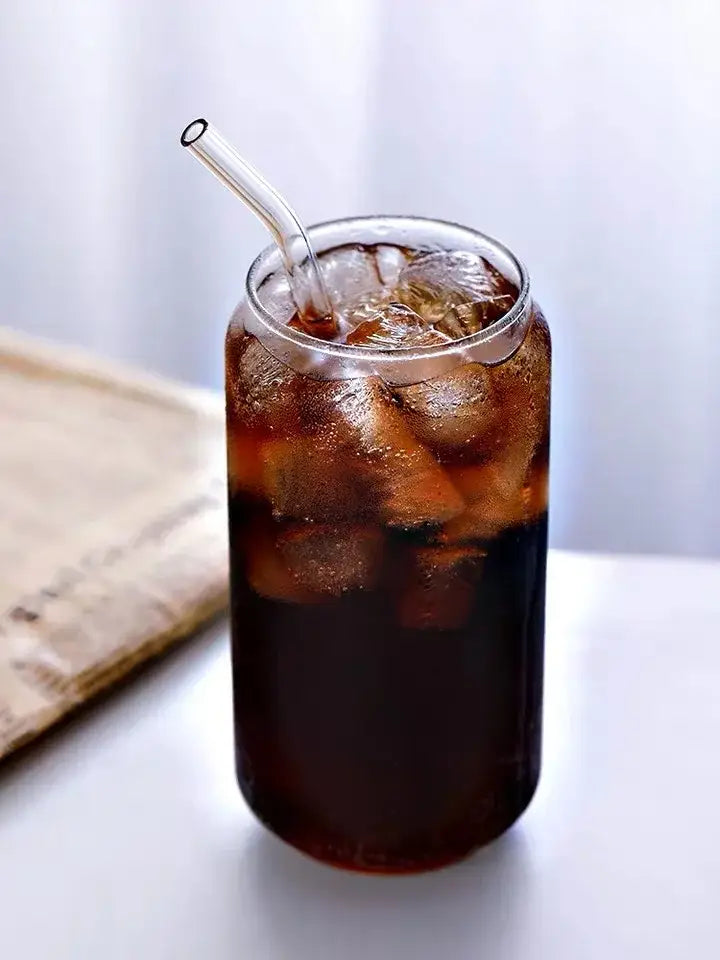 Aesthetic drinking glasses set with lids and transparent straws featuring a tall clear glass filled with dark iced cola