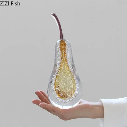 A translucent green and gold glass fruit sculpture by zizi fish with bubbles and a maroon stem as a sculpture desk ornament