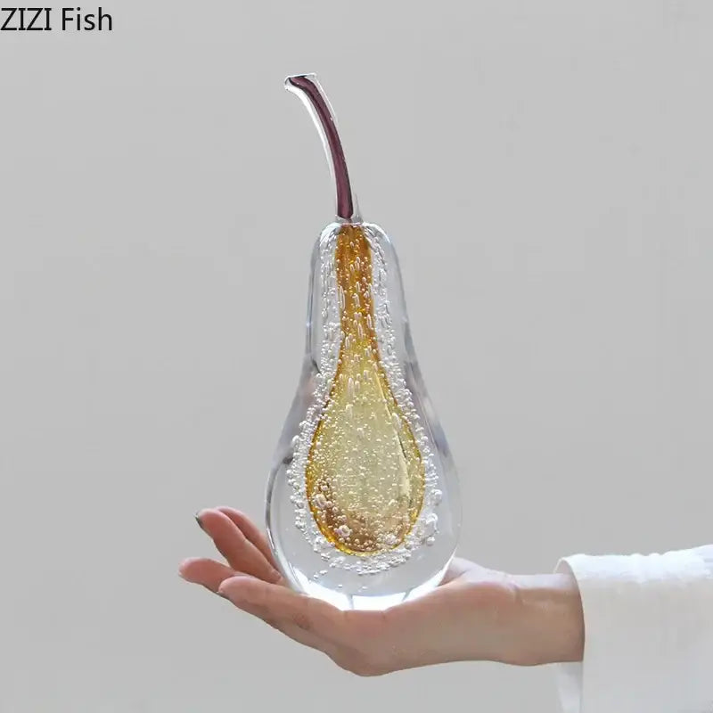 A translucent green and gold glass fruit sculpture by zizi fish with bubbles and a maroon stem as a sculpture desk ornament
