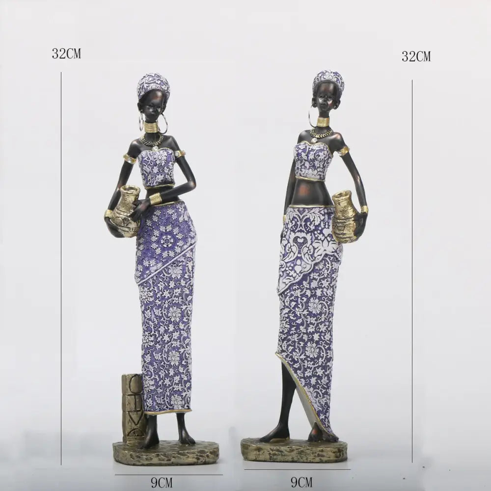 Two 32cm tall decorbites african woman sculpture figurines in purple white patterned dresses with gold accents on textured bases