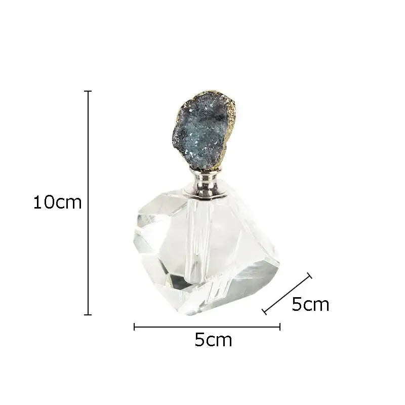 A clear faceted crystal perfume bottle with a silver neck and dark blue druzy agate stone stopper for essential oils