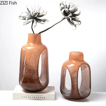 Two terracotta amber and brown dual color glass vases with glossy finish and cut-out panels holding black-and-white decorbites dual color flowers