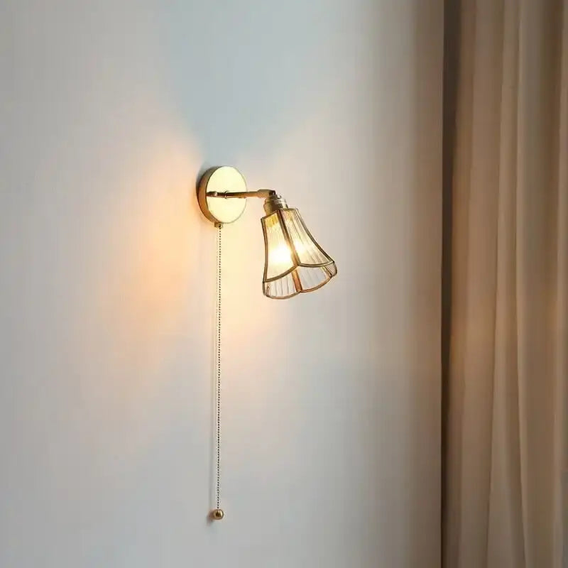 Gold-toned wall sconce with fluted glass shade and adjustable arm complementing amber and cream glass pendant light for dining room