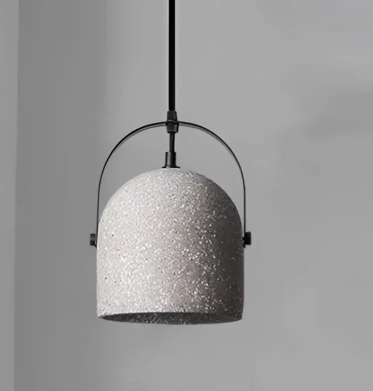 Gray speckled concrete pendant light with black metal frame paired with amber and cream geometric glass pendant light for dining room