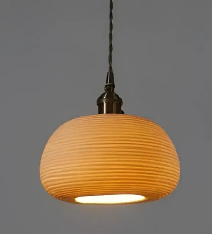 Amber and cream geometric glass pendant light with warm-toned ribbed ceramic and brass fixture for dining room