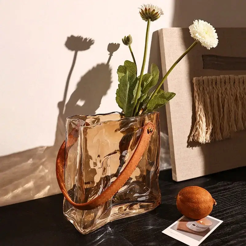 Translucent amber bag shape glass vase with textured surface and tan leather handle for living room decor