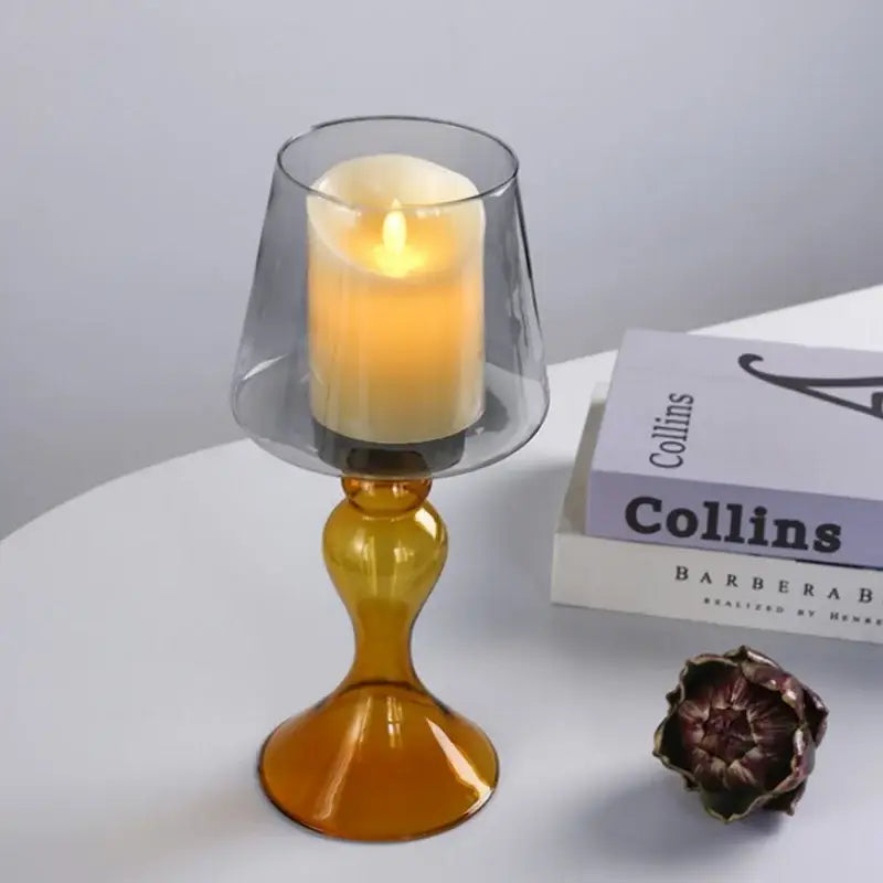A translucent amber decorbites geometric glass candle holder with flared top holding an illuminated white led candle