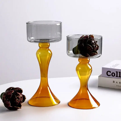 Two translucent amber decorbites geometric glass candle holders with flared base, one holding a dark dried flower