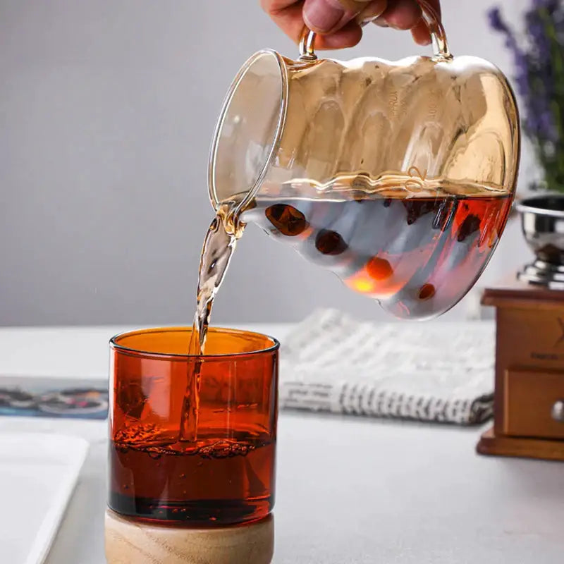 Amber fluted glass percolator coffee pot with reusable filter and gold-toned handles pouring into orange glass