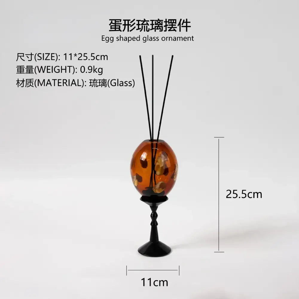 Translucent amber geometric circle glass reed diffuser with golden leaf patterns on black metal stand for living room decor
