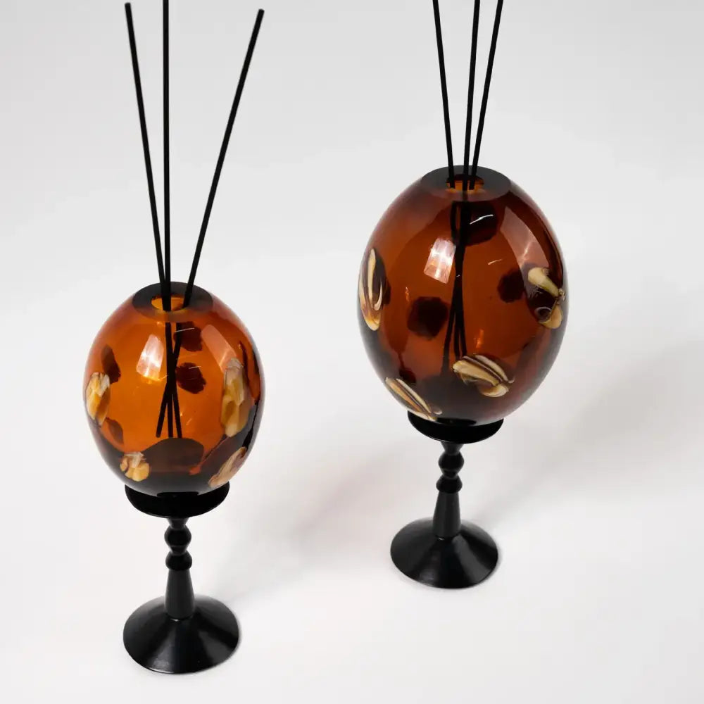 Amber geometric circle glass reed diffuser holders with swirling gold and brown patterns on black metal stands decorbites geometric circle