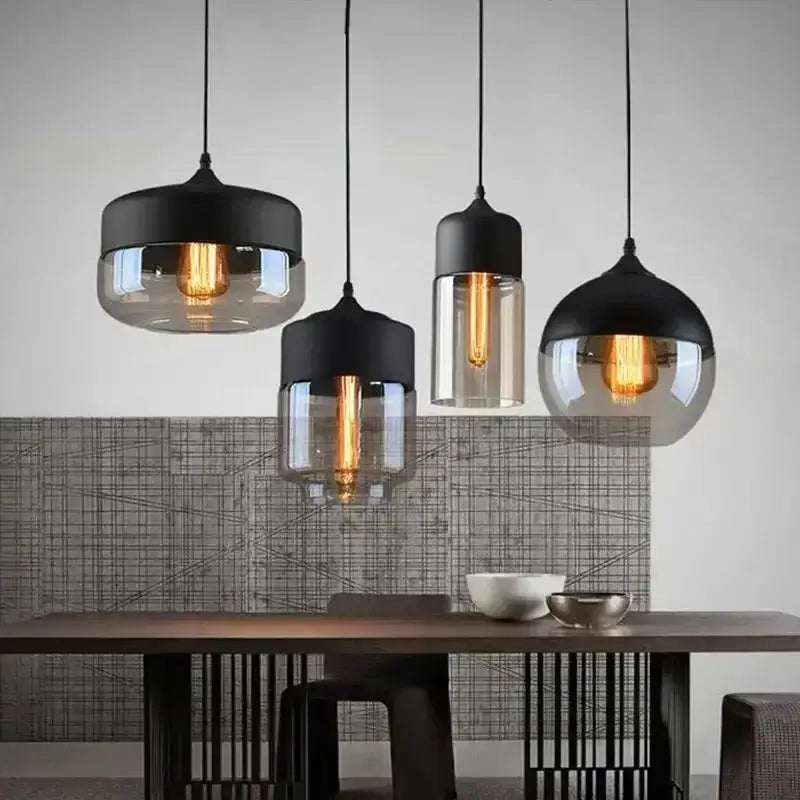 Set of four modern pendant light fixtures with black metal tops and amber smoked glass shades for dining room