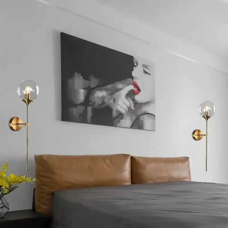Black-and-white canvas artwork with bold red lips and tattooed arms above bed featuring amber glass ball sconce light brass finish