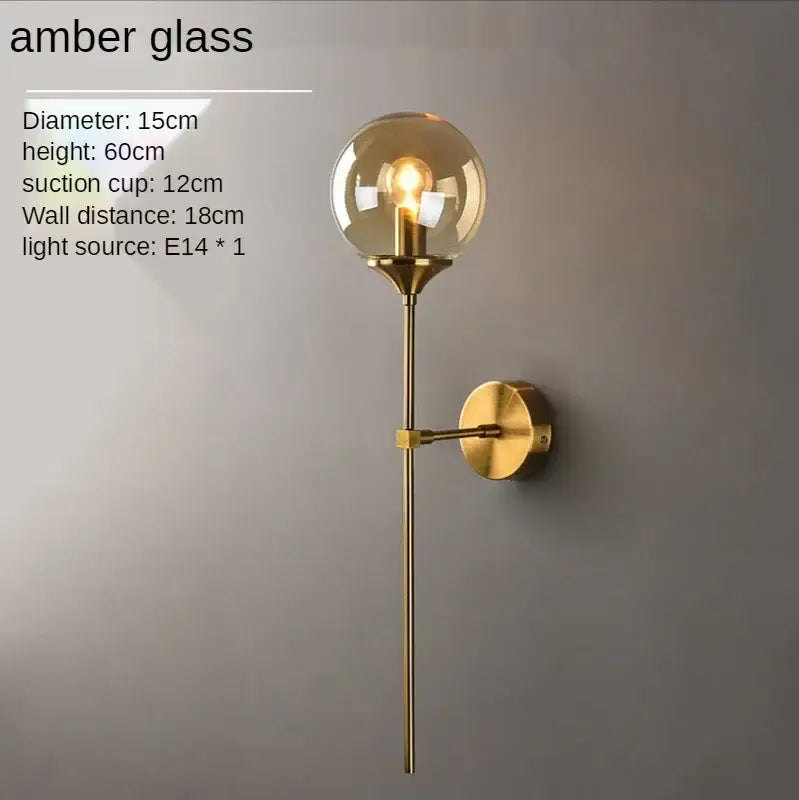 A sleek brass finish glass ball sconce light with an amber globe for elegant bedroom decorbites decor