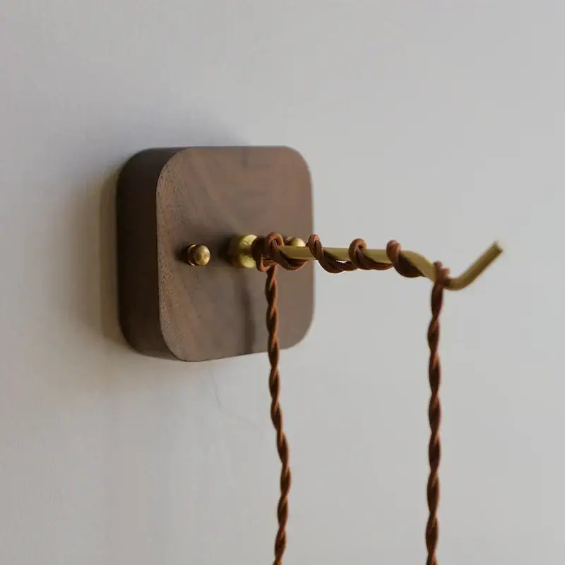 Dark wood wall-mounted hook with brass finish and twisted brown cord for amber glass ceramic ball led wall lights decorbites ceramic ball