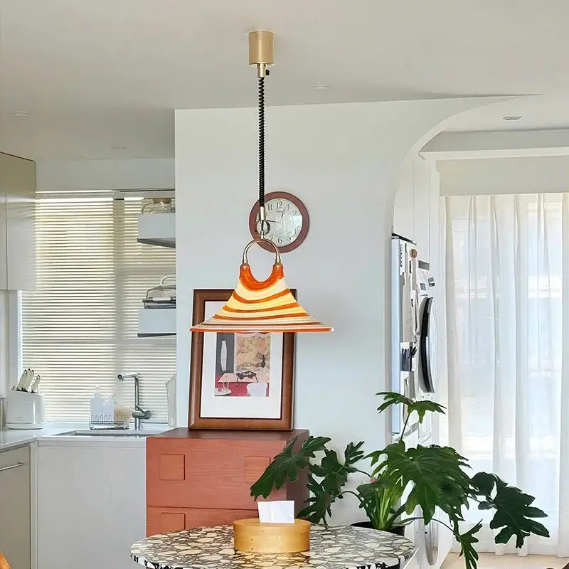 A vibrant orange and white decorbites liftable trumpet chandelier with brass finish and black cord for dining room decor