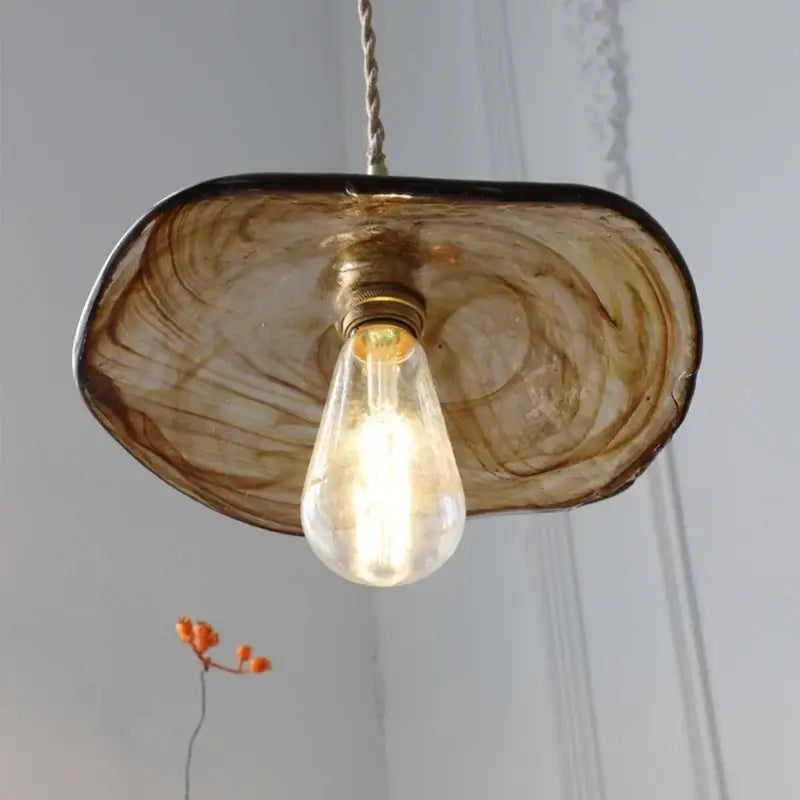 Amber glass pendant light with brass knob switch featuring warm amber swirl and exposed Edison bulb for dining room decorbites brass knob