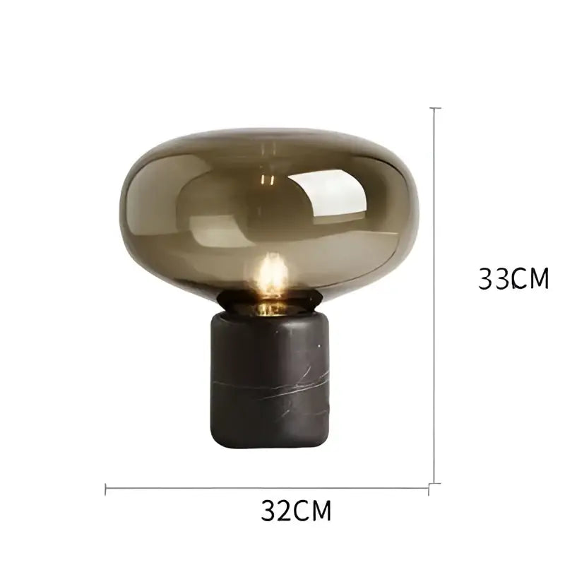 A sleek nordic table lamp with a translucent amber glass dome and a dark marble base for modern interiors