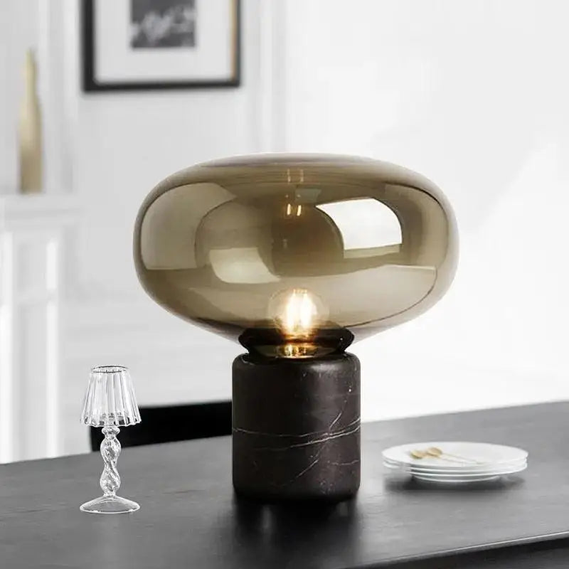 A sleek nordic table lamp with a translucent amber glass dome and a dark marble base for modern interiors