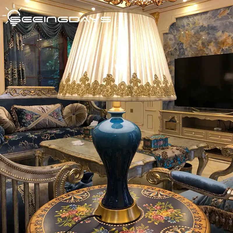 Deep blue ceramic table lamp with gold accents and a cream pleated shade for decorbites American luxury bedroom decor